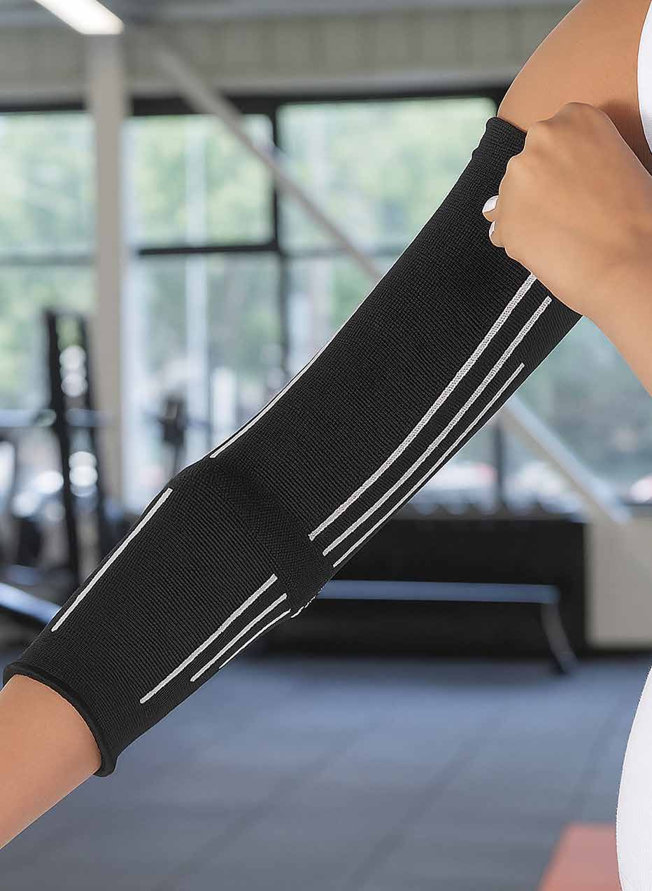 Model pulling on a black arm compression sleeve with white stripe detailing over the forearm.