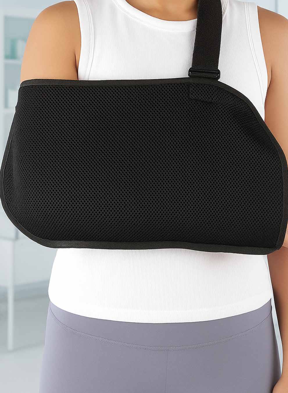 Black mesh standard arm sling worn across the body supporting the forearm.