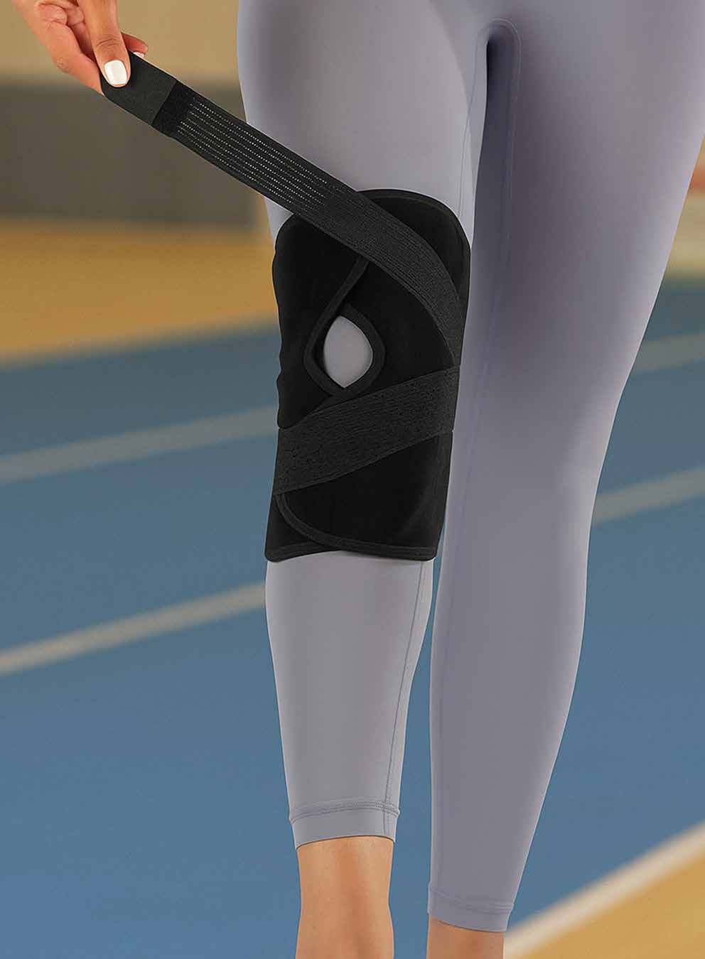 Model wrapping the black elastic knee support with an open patella opening around the knee.