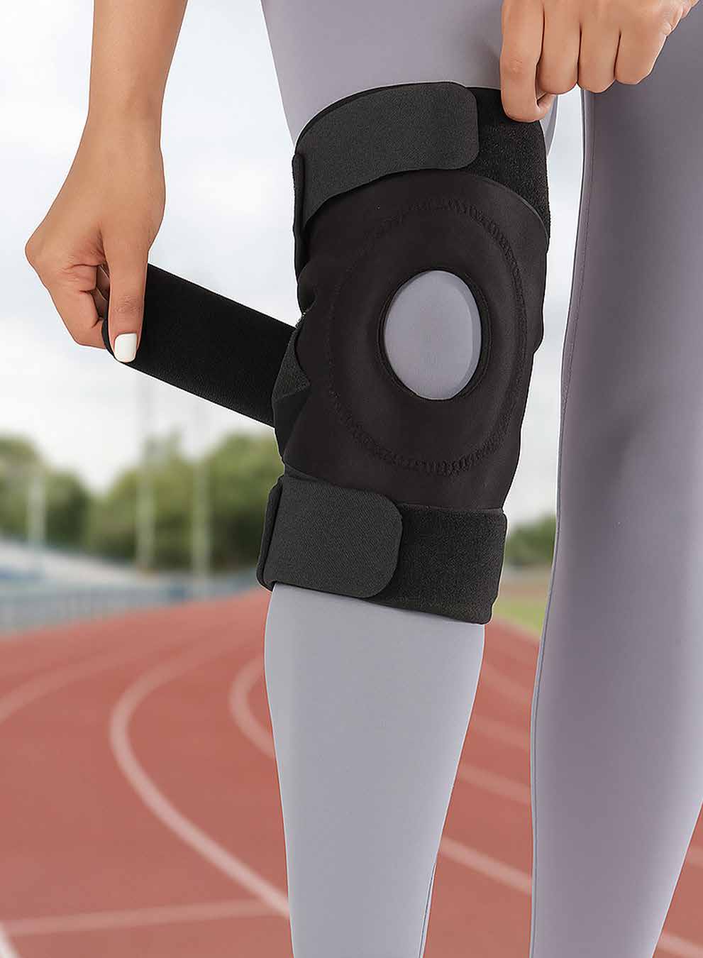 Model securing the black neoprene open-patella knee brace above the calf.