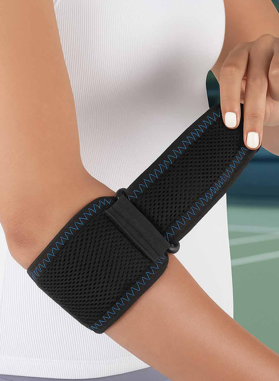 Model adjusting the black mesh tennis elbow strap with blue stitching around the forearm.